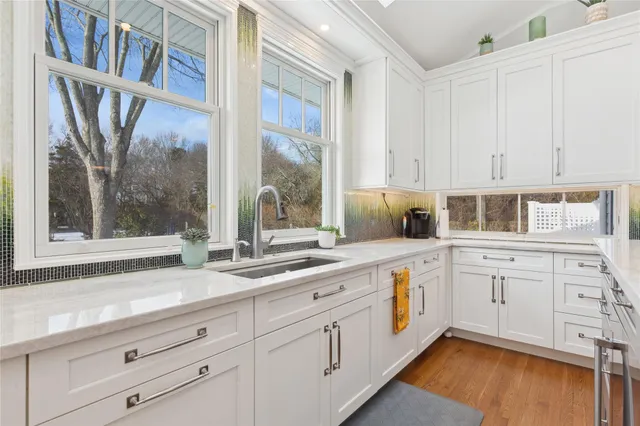 a kitchen that has a sink and a stove with wooden floor