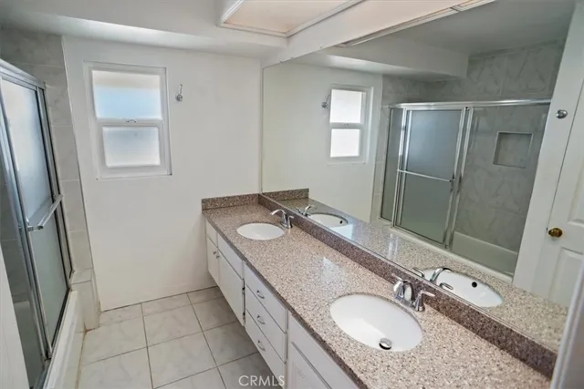 a bathroom with a granite countertop double vanity sink and mirror