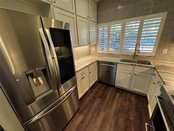 a kitchen with stainless steel appliances a refrigerator sink and wooden floor