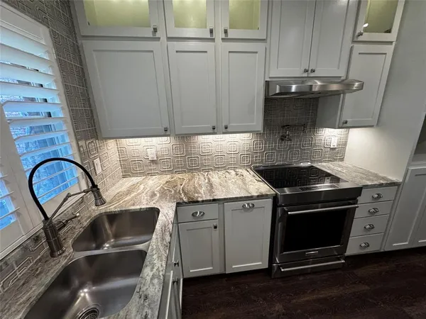 a kitchen with granite countertop a sink stainless steel appliances and cabinets