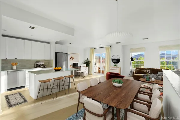 a living room with stainless steel appliances furniture a rug and a kitchen view