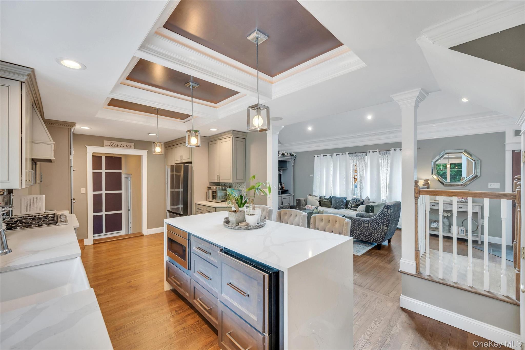 19 Joan Road Bay Shore, NY 11706 - Photo 8 of 50 Spacious open-concept kitchen featuring light-toned cabinetry, a waterfall-edge island with an integrated microwave, quartz countertops, and recessed ceiling lighting