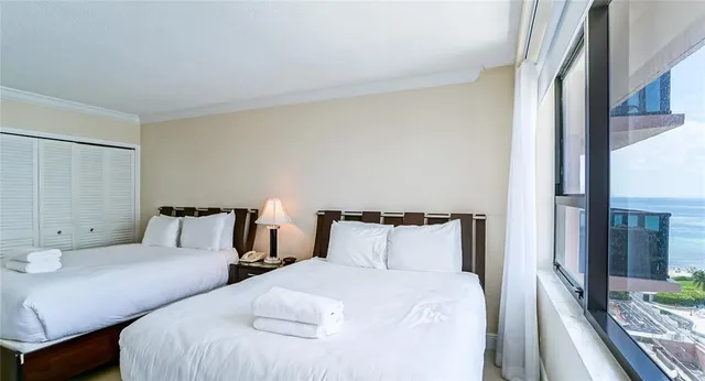 a bedroom with two beds and a large mirror next to a large window