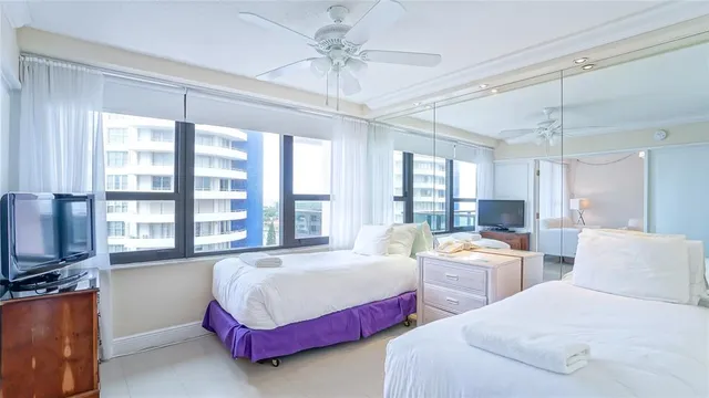 a bedroom with two beds and large windows