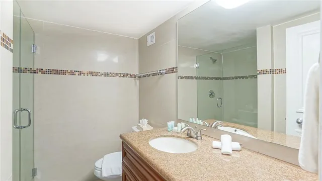 a bathroom with a granite countertop sink a toilet and shower