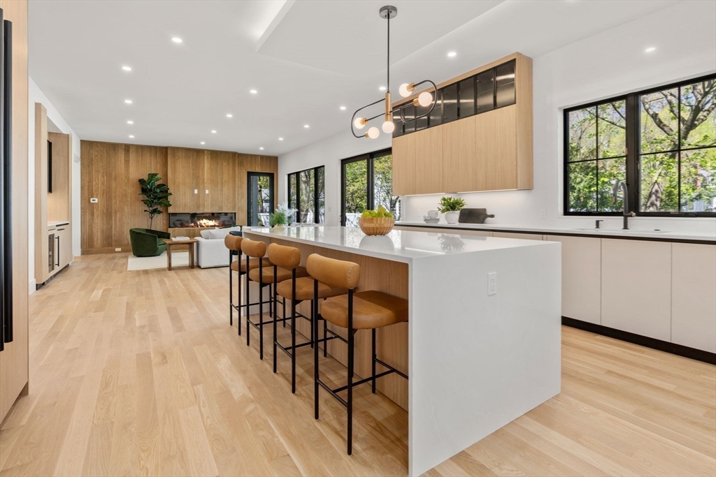 470 Quinobequin Road Newton, MA 02468 - Photo 6 of 37 a kitchen with stainless steel appliances kitchen island granite countertop a stove top oven a sink a dining table and chairs with wooden floor