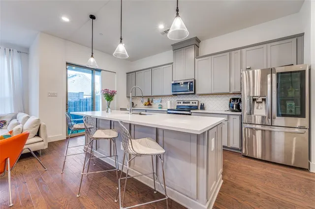 a kitchen with stainless steel appliances granite countertop a stove a sink a refrigerator wooden floor and white cabinets