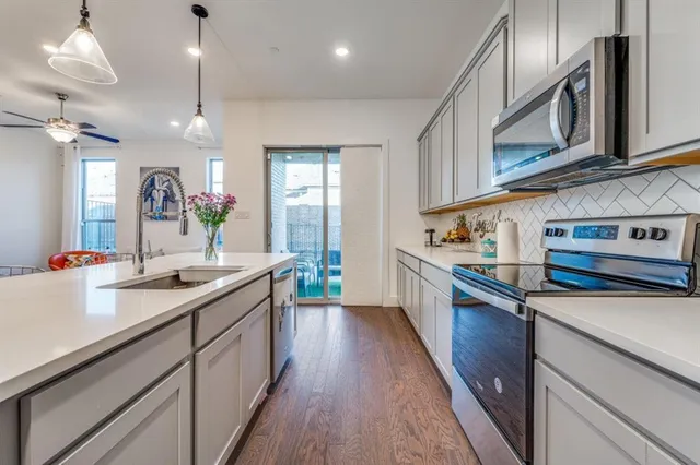 a kitchen with stainless steel appliances granite countertop a sink a stove and a wooden floors