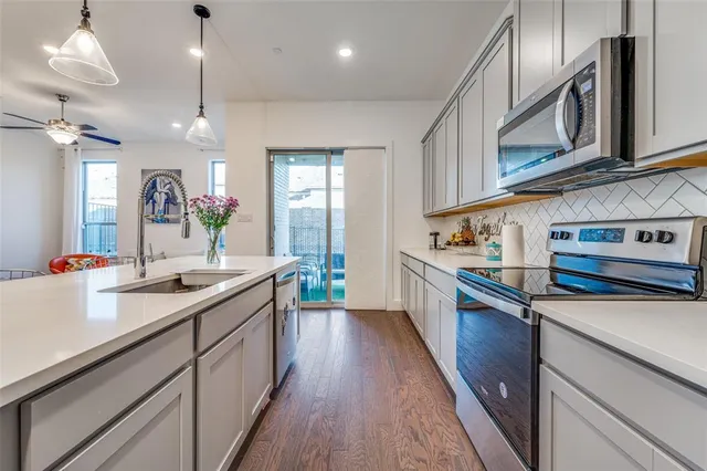 a kitchen with stainless steel appliances granite countertop a sink a stove and a wooden floors