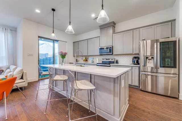 a kitchen with stainless steel appliances granite countertop a stove a sink a refrigerator wooden floor and white cabinets