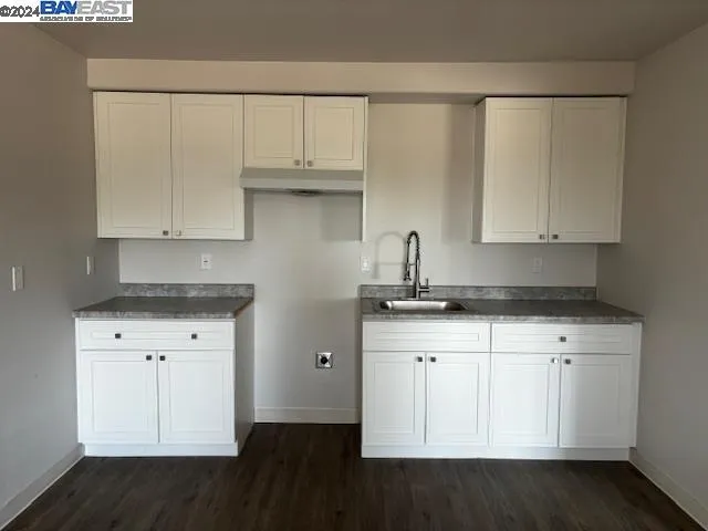 a kitchen with granite countertop white cabinets and a sink