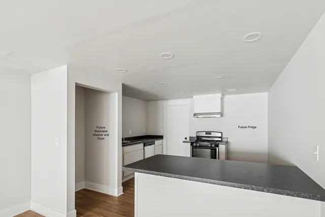 a kitchen with granite countertop a refrigerator and a stove top oven