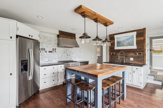 a kitchen with stainless steel appliances granite countertop a kitchen island a stove a table and chairs