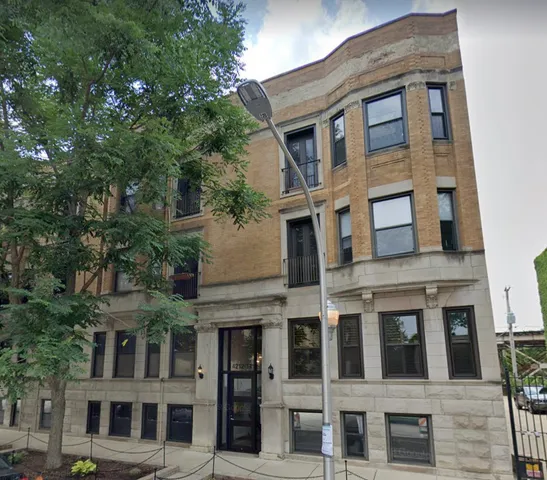 a front view of a building with a tree