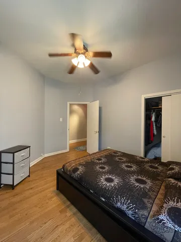 a bedroom with a bed and dresser with wooden floor