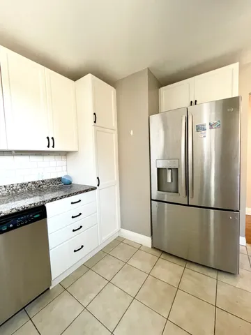 a kitchen with granite countertop a refrigerator and a stove top oven