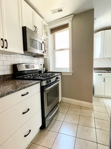 a kitchen with granite countertop a stove a sink and a microwave