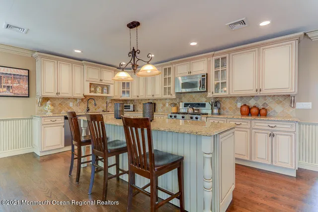 a kitchen with stainless steel appliances kitchen island granite countertop a table chairs sink and cabinets