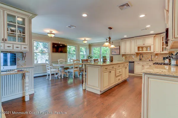 a kitchen with stainless steel appliances kitchen island granite countertop a stove top oven a sink a dining table and chairs