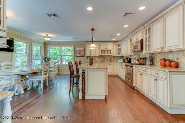 a kitchen with stainless steel appliances granite countertop a stove top oven a sink dishwasher a dining table and chairs with wooden floor