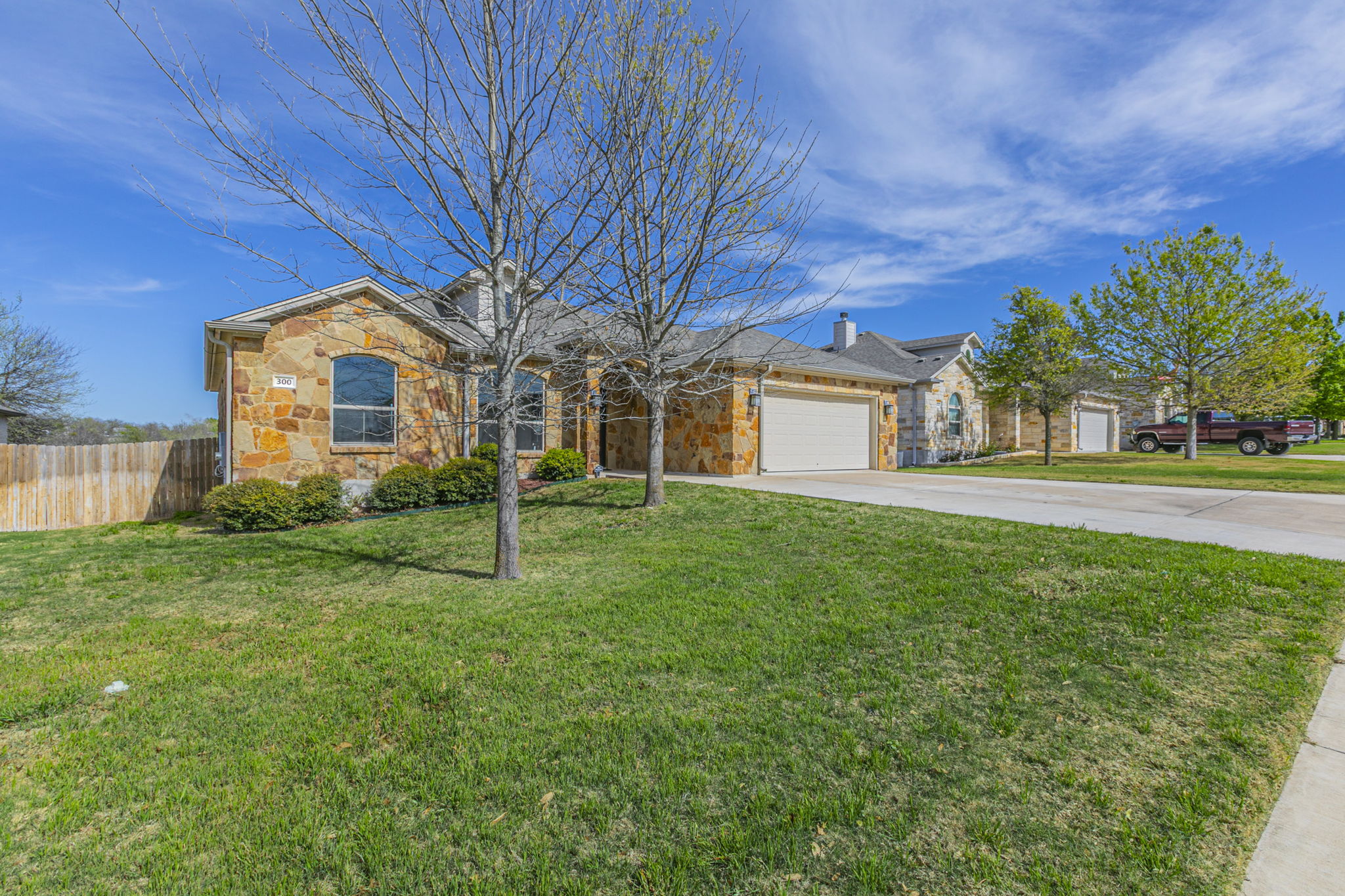 300 Magan Lane Jarrell, TX 76537 - Photo 23 of 33 View of front of home featuring stone siding, driveway, a garage, and a chimney
