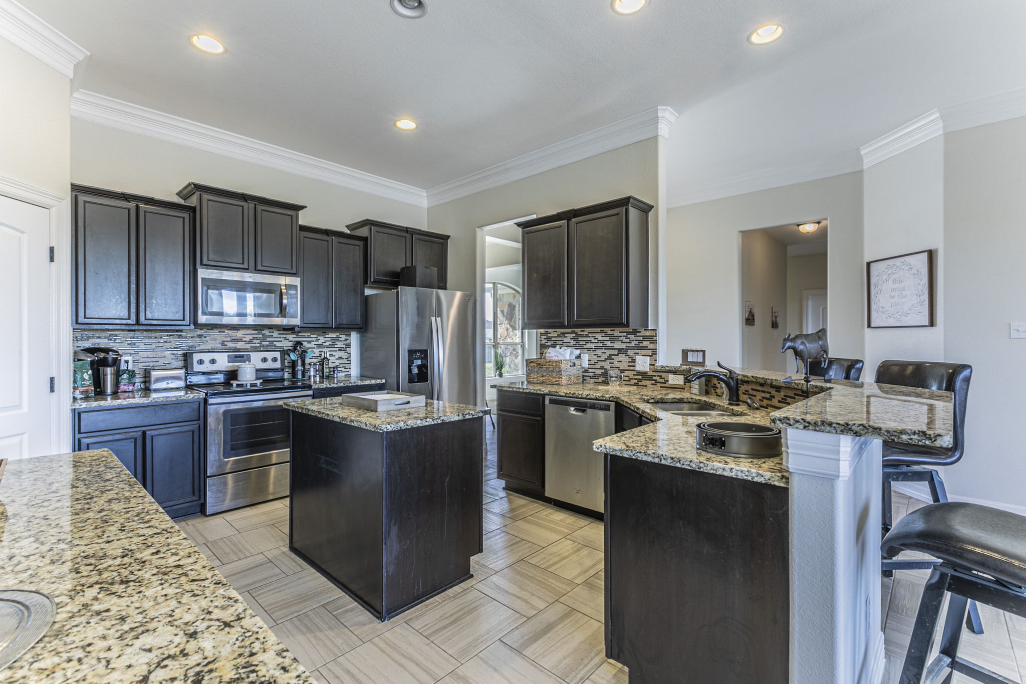 300 Magan Lane Jarrell, TX 76537 - Photo 5 of 33 Kitchen with a kitchen island, a peninsula, stainless steel appliances, a kitchen breakfast bar, and decorative backsplash