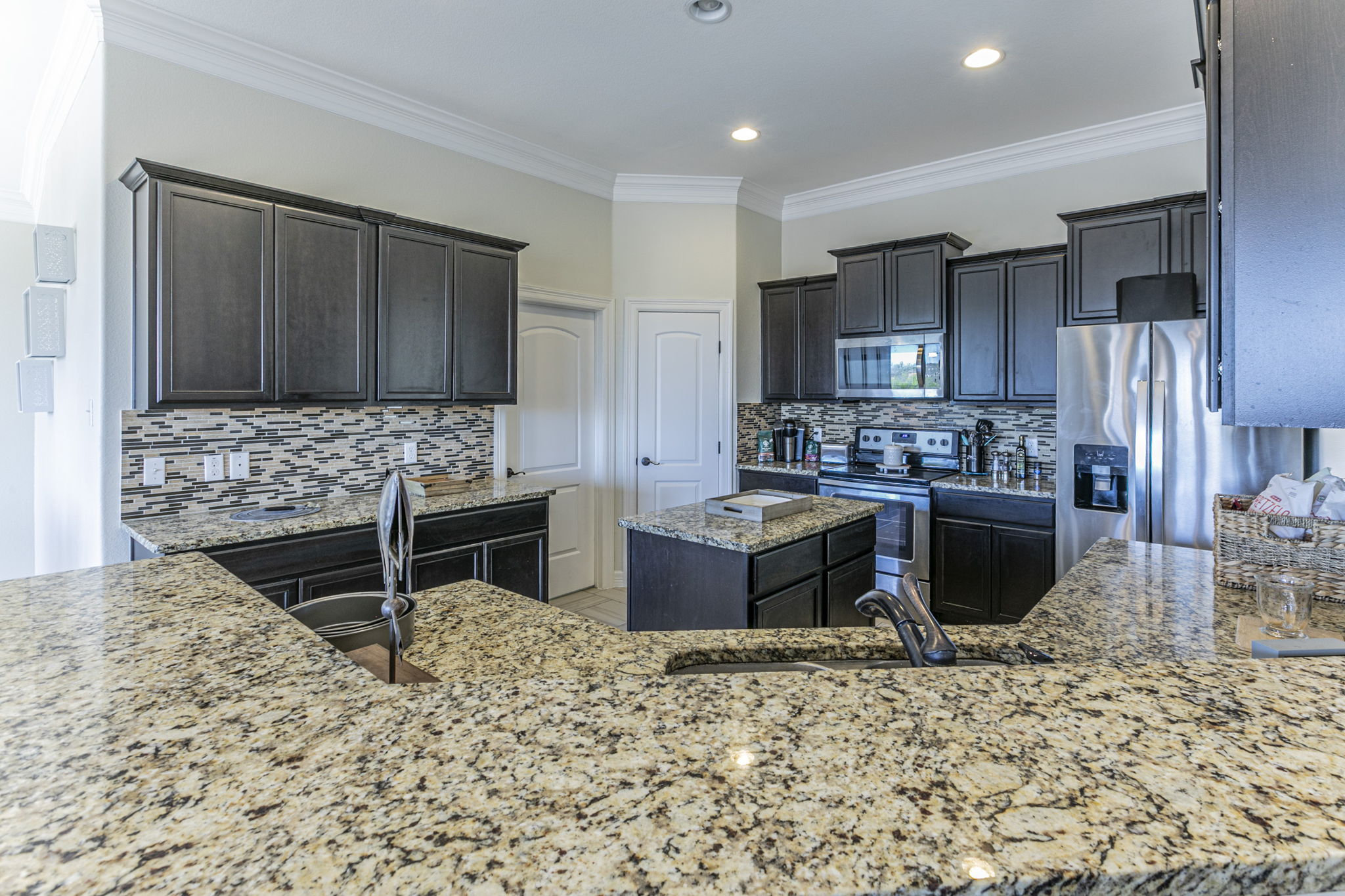 300 Magan Lane Jarrell, TX 76537 - Photo 8 of 33 Kitchen with stainless steel appliances, ornamental molding, light stone counters, a center island, and tasteful backsplash