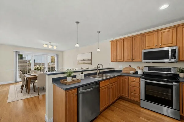 a kitchen with stainless steel appliances granite countertop a stove top oven a sink dishwasher a dining table and chairs with wooden floor