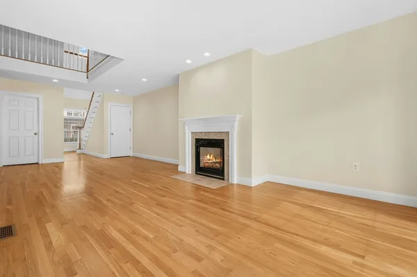 a view of an empty room with wooden floor and a fireplace