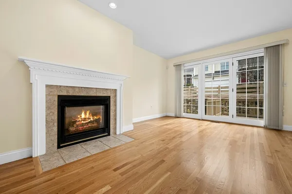 a view of an empty room with wooden floor fireplace and a window