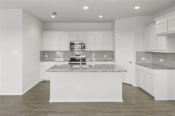 a kitchen with stainless steel appliances granite countertop a sink dishwasher a refrigerator and a stove with wooden floor