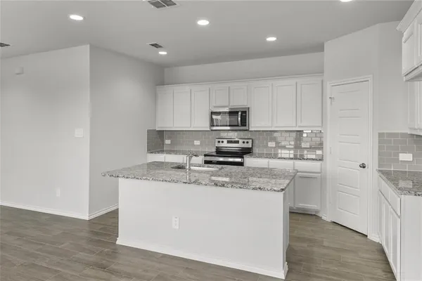 a kitchen with stainless steel appliances granite countertop a sink a stove a refrigerator and cabinets