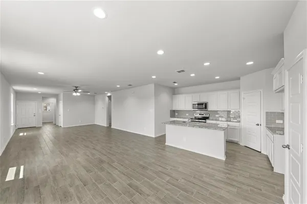 a kitchen with stainless steel appliances granite countertop a sink a stove a refrigerator and white cabinets