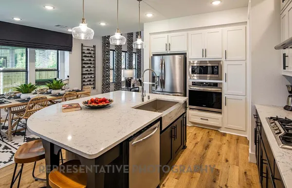 a kitchen with stainless steel appliances a dining table chairs stove refrigerator and cabinets