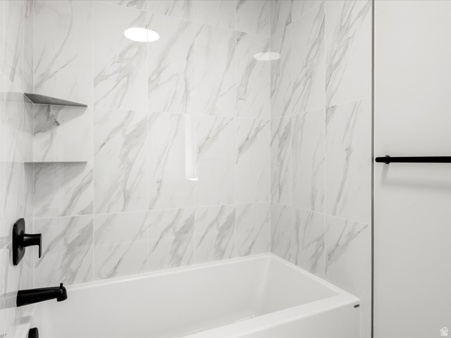 1159 North Broad Hollow Road Garden City, UT 84028 - Photo 42 of 55 White bathtub with matte black fixtures, surrounded by large format marble-look tile