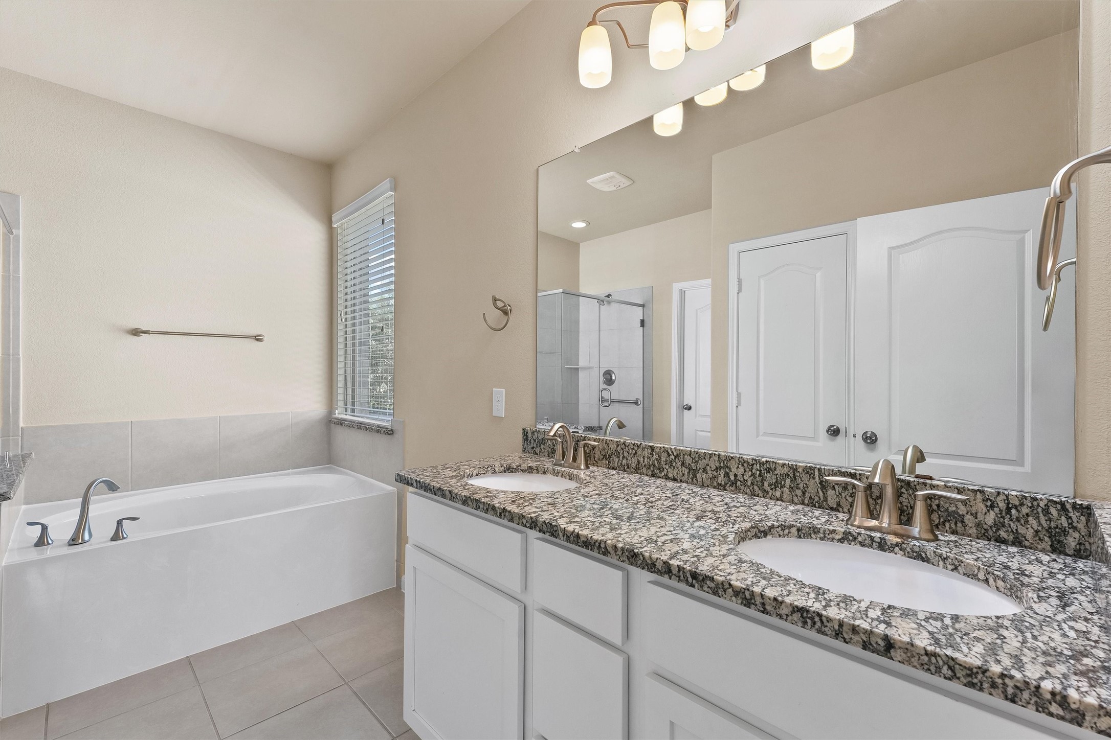 3841 Enchanted Timbers Lane Spring, TX 77386 - Photo 14 of 28 a bathroom with a granite countertop bathtub a double vanity sink and a mirror