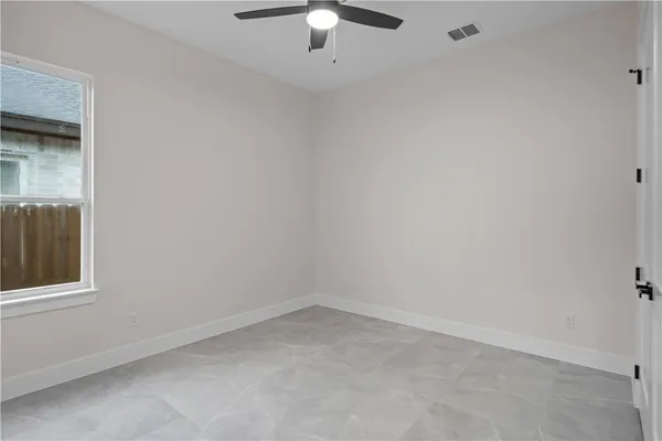 an empty room with a chandelier fan and windows