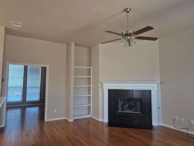 a view of a livingroom with a fireplace a ceiling fan and wooden floor