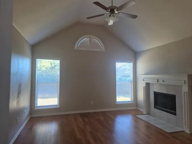 an empty room with wooden floor fan and windows