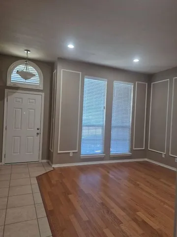 an empty room with wooden floor cabinet and windows
