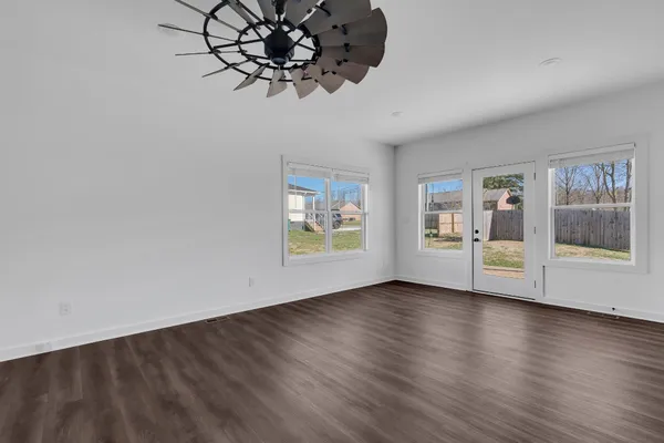 a view of an empty room with a window and wooden floor