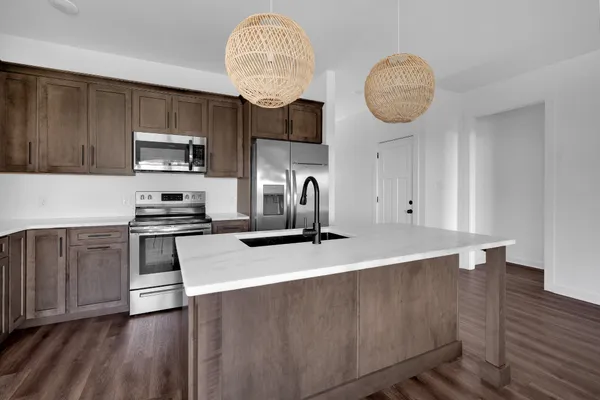 a kitchen with kitchen island granite countertop a sink a stove and wooden floors