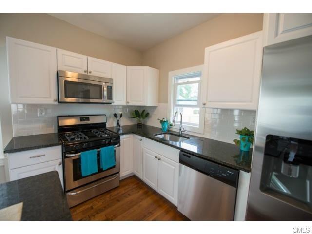 51 Canaan Road Stratford, CT 06614 - Photo 1 of 1 a kitchen with granite countertop a stove a microwave a sink a refrigerator and cabinets