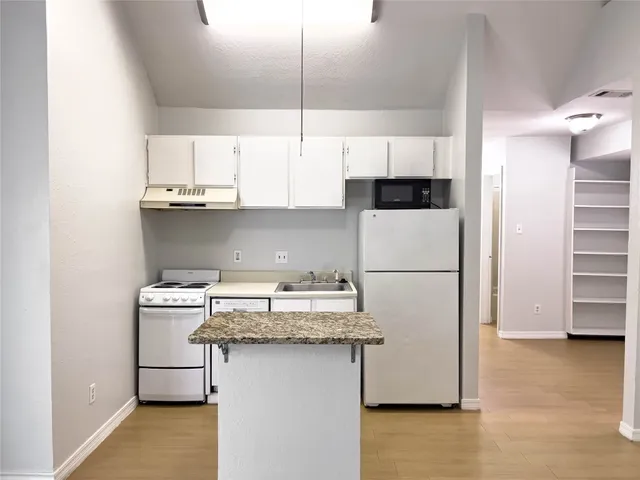 a kitchen with a sink a refrigerator and cabinets