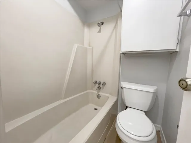 a white toilet sitting next to a bathtub