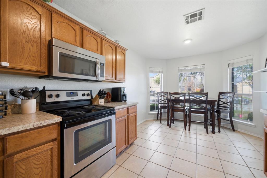 2008 Times Road Heartland, TX 75126 - Photo 13 of 28 a kitchen with stainless steel appliances granite countertop a stove top oven a sink a dining table and chairs