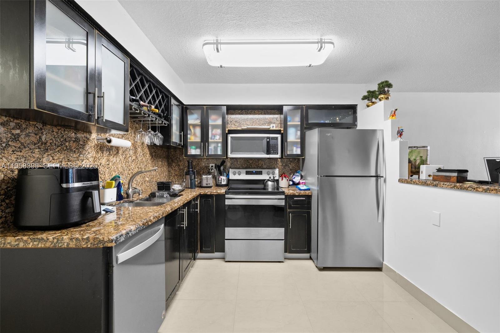 4011 Meridian Avenue, Unit 38 Miami Beach, FL 33140 - Photo 2 of 22 a kitchen with stainless steel appliances granite countertop a refrigerator a stove a sink and a microwave