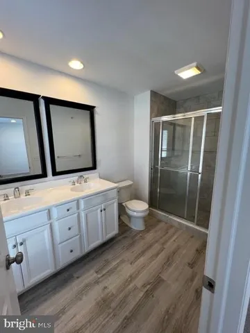 a spacious bathroom with a double vanity sink a mirror and a toilet