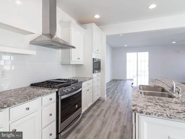 a kitchen with stainless steel appliances granite countertop a stove a sink and a refrigerator