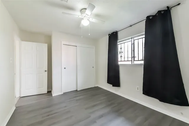 an empty room with wooden floor and ceiling fan